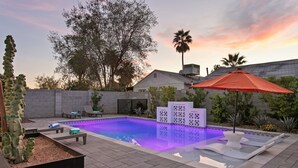 A swimming pool with a tiled deck, lounge chairs, and a decorative fence. - Freshly Renovated Midtown Phoenix Retreat with Pool (Phoenix)
