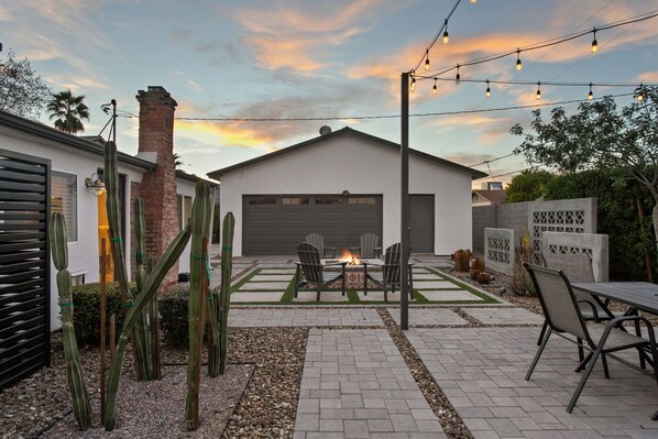 Un patio con fogón, mobiliario exterior y cactus.