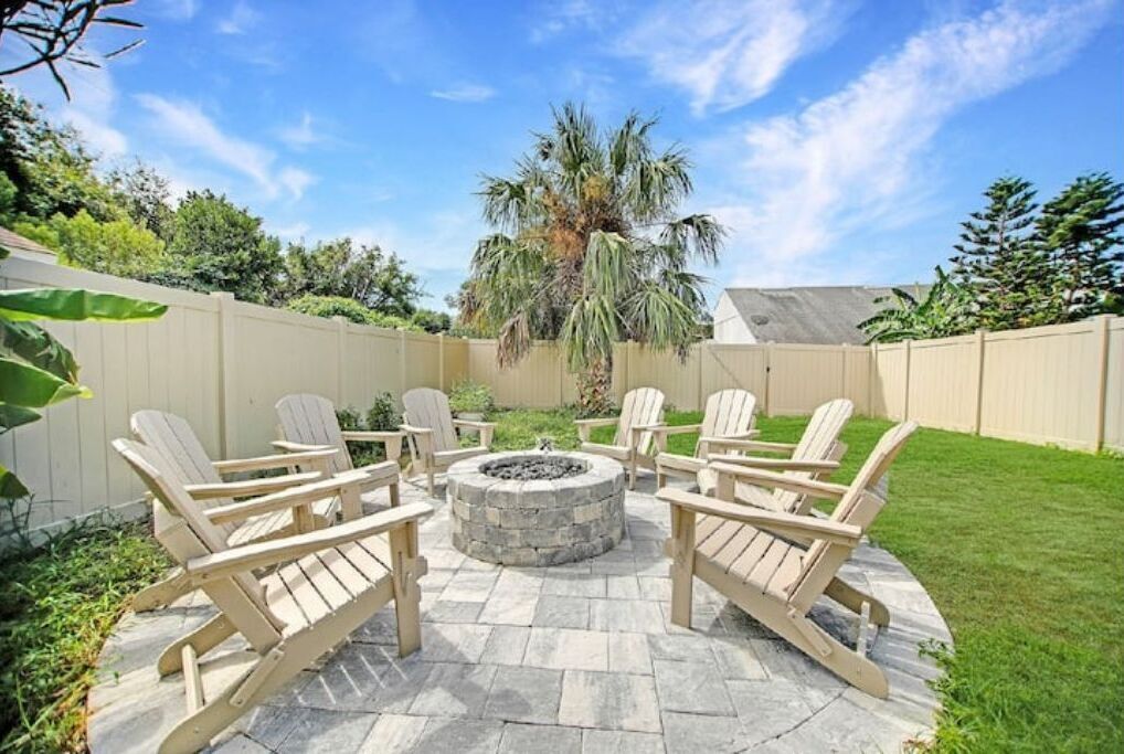 A patio with Adirondack chairs arranged around a stone fire pit.