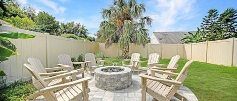 A patio with Adirondack chairs arranged around a stone fire pit.