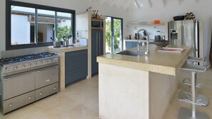 Een moderne keuken met een ingebouwde kookplaat, een groot eiland met een spoelbak, en een koelkast.
