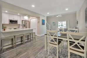 A modern kitchen with white cabinets, stainless steel appliances, and a central island.