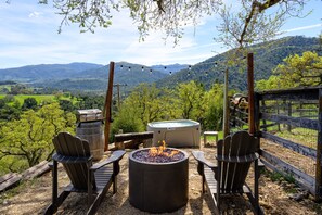 A fire pit with chairs and a hot tub in a scenic outdoor setting. - Unique Off-Grid experience with Stunning Views Close to Wine Tasting (Carmel Valley)