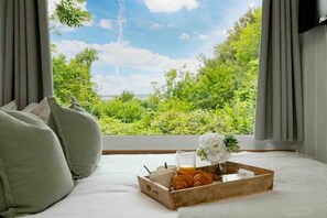 Een slaapkamer met een bed, een dienblad met croissants, een glas sinaasappelsap en een bloem.
