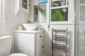 Een badkamer met een witte wastafel, spiegel en handdoekhouder.