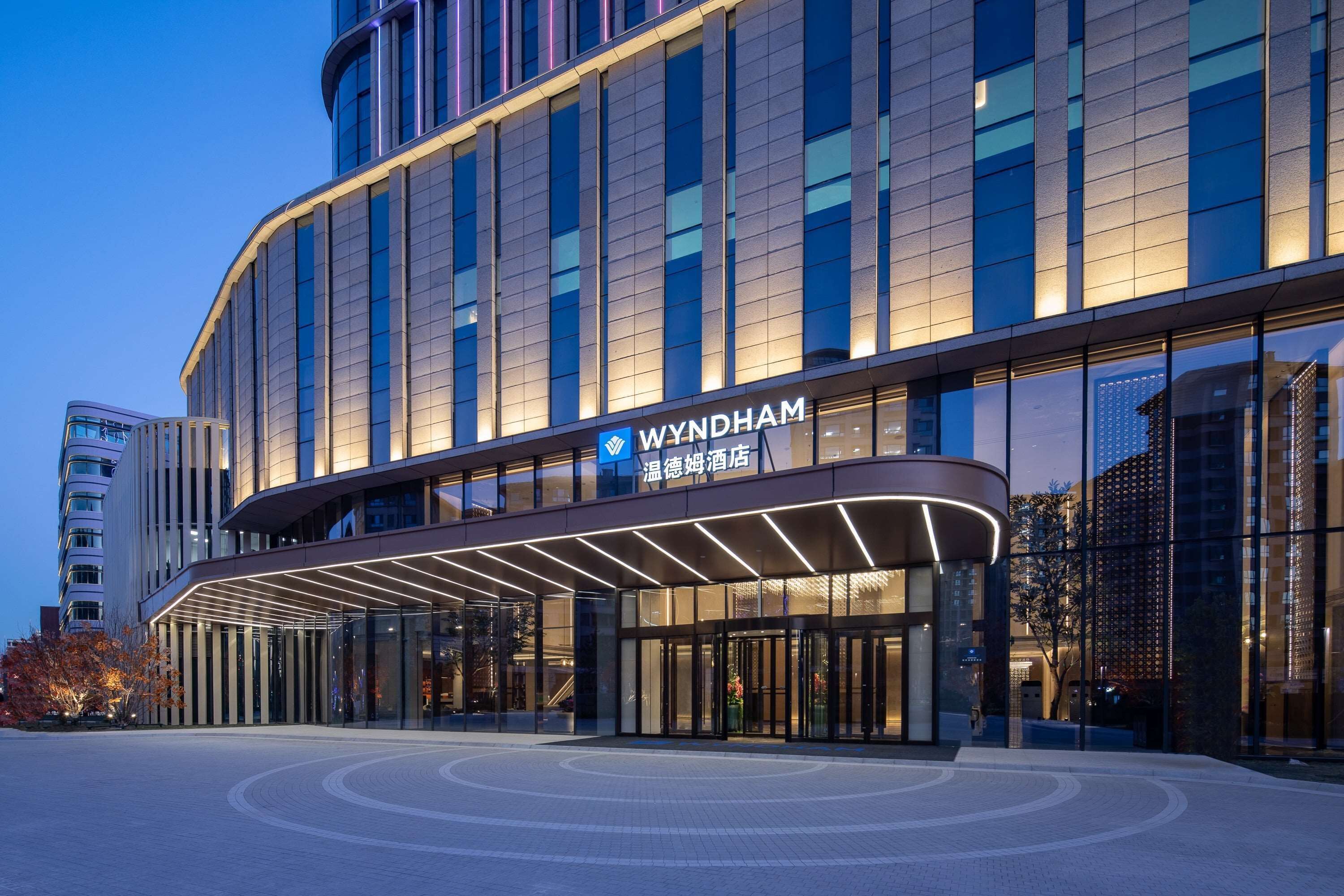 Et moderne hotel med en buet indgang og et tydeligt skilt.