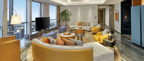 Een moderne hotel lobby met een gebogen bank, een televisie, een grote plant en uitzicht over de stad.