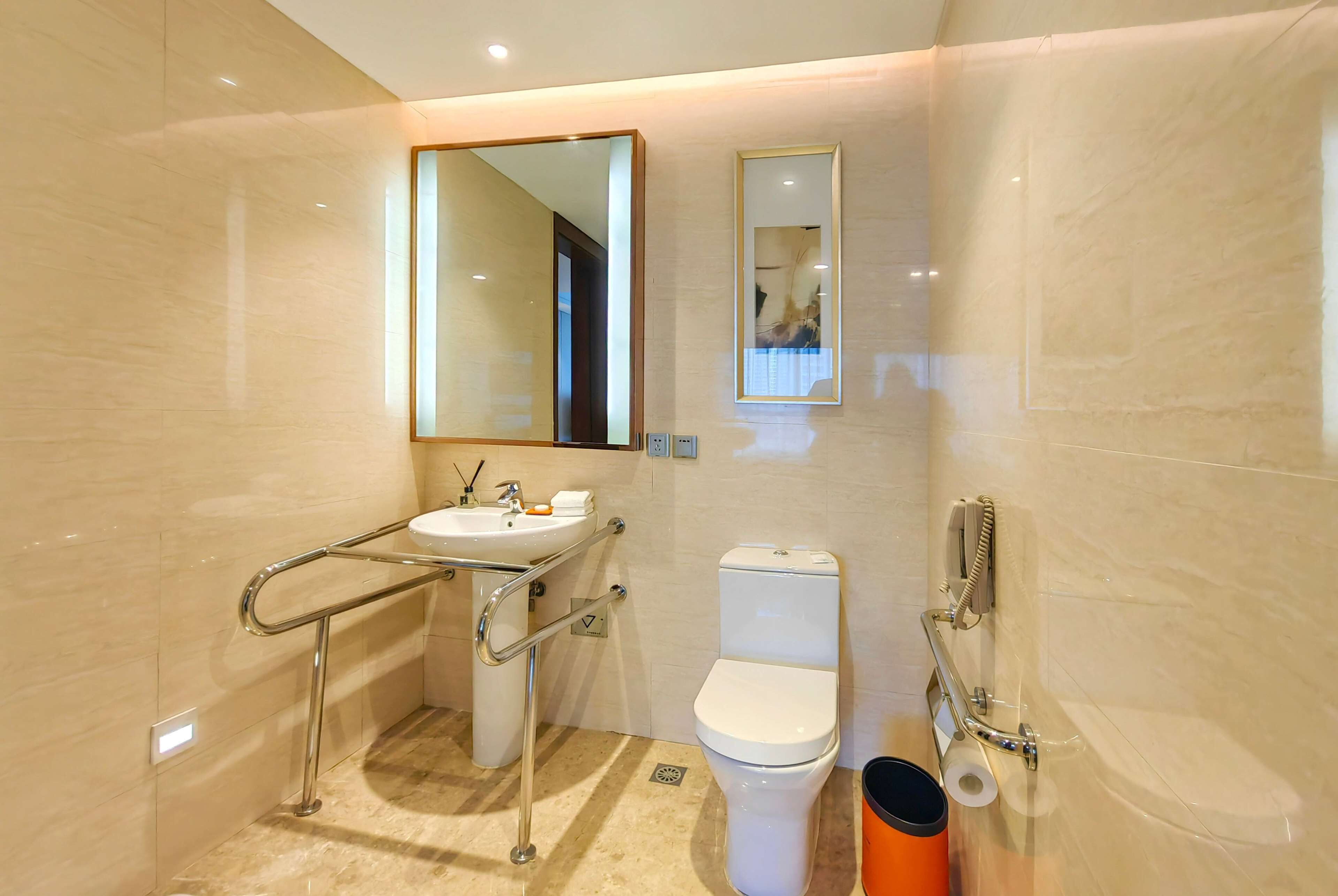 Une salle de bain moderne équipée d’un lavabo, de toilettes et d’une barre d’appui.