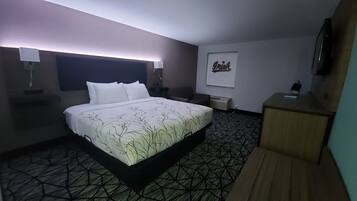Una habitación de hotel con una cama grande, un escritorio, una silla y un televisor montado en la pared.