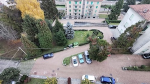 An aerial view of a residential area with a parking lot, multiple cars, and surrounding trees. - Lovely view - apartment (Albizzate)