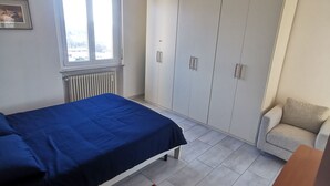 A bedroom with a bed, a wardrobe, a radiator, a window, and a red rug. - Lovely view - apartment (Albizzate)