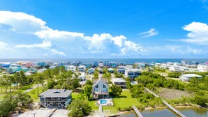 A coastal residential area with houses, a swimming pool, and a dock extending into the water. - Lagoon Front | Private Pool and Pier | Pet Friendly (Gulf Shores)