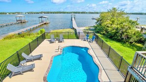 A swimming pool with a deck, lounge chairs, and a view of a lake. - Lagoon Front | Private Pool and Pier | Pet Friendly (Gulf Shores)
