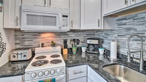 Una cucina moderna con mobili bianchi, un forno a microonde, un fornello, un tostapane e un lavello.