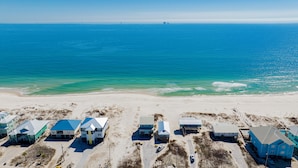 Une zone côtière comprenant plusieurs maisons de plage, une plage de sable et l’océan.