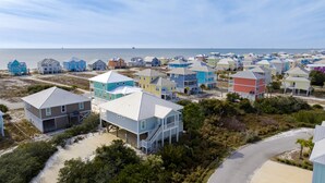 Una zona residencial costera con casas coloridas, algunas elevadas sobre pilotes, y una vista despejada del océano.