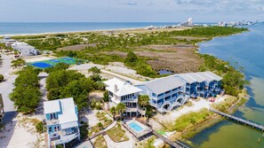 A coastal hotel with multiple buildings, a swimming pool, and a beach area.