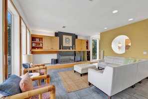 A modern living room with a fireplace, white sofa, and wooden shelves. - Waterfront Luxury | Private Pool, Pier, Boat Lift | Pet Friendly (Perdido Key)