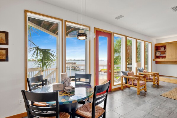 A dining area with a glass table, chairs, and a view of the sea.