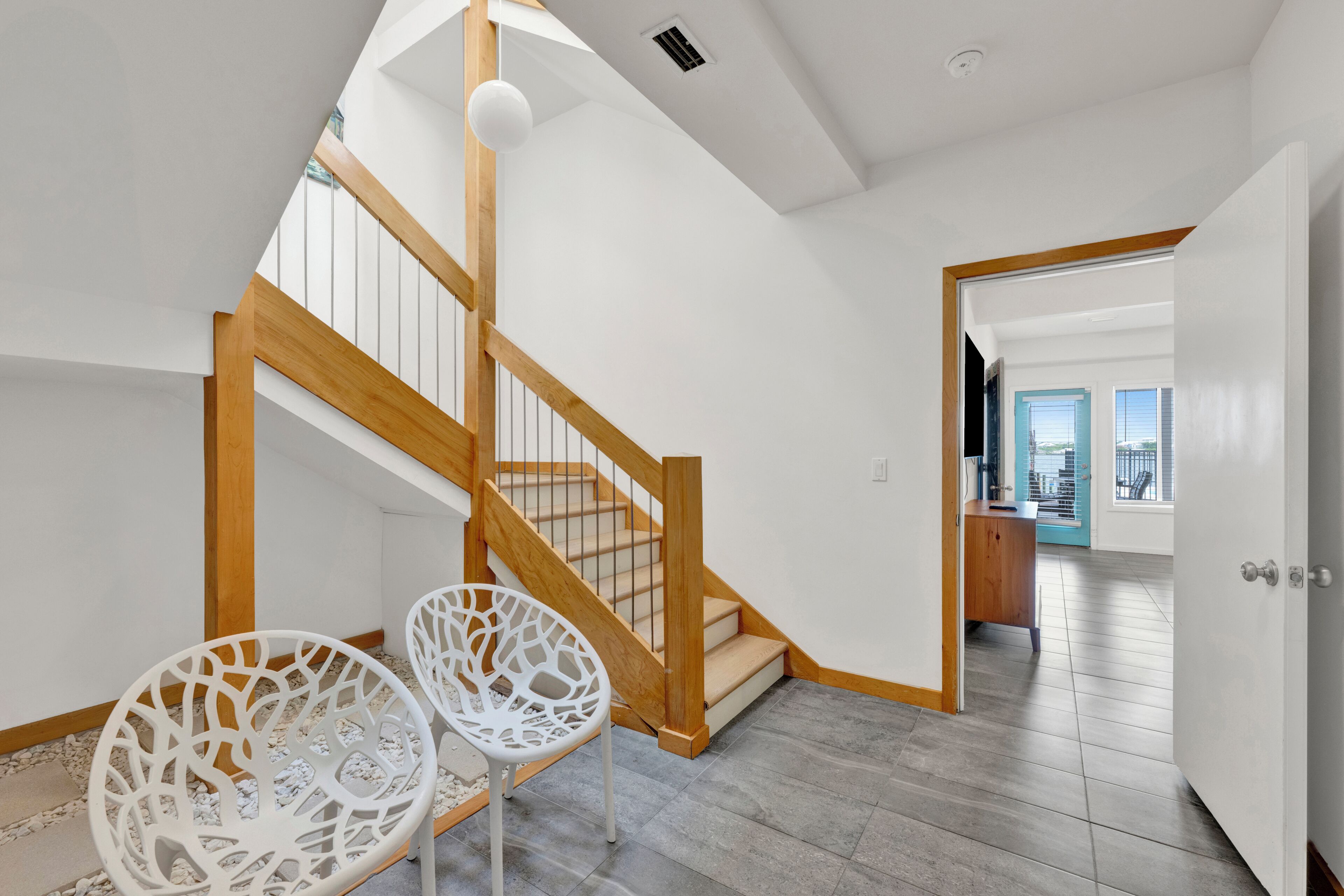 A staircase with wooden railings, white walls, and a view into another room.