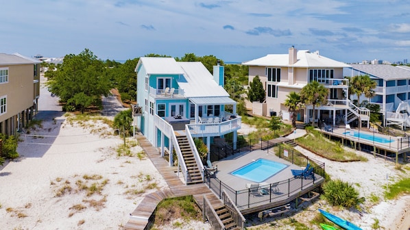 A beachfront property with a pool, multiple levels, and a deck area.