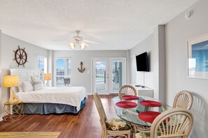 Ein Schlafzimmer mit Bett, Nachttischlampen, Deckenventilator und Blick ins Freie durch eine Tür.