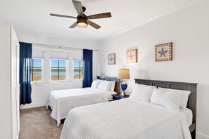 A hotel room with two beds, a ceiling fan, a window with curtains, and wall decorations. - Luxury Retreat | Private Pool | Resort Style Amenities (Gulf Shores)
