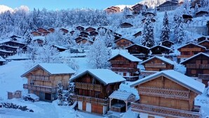 Un village enneigé, avec des chalets en bois, chacun doté d’un balcon et d’un petit porche.