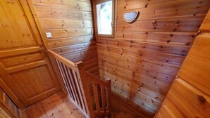 Un intérieur en bois, avec un escalier en bois et une petite fenêtre.