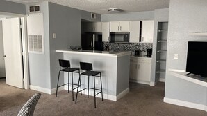 A compact kitchen with a central island, bar stools, and a flat-screen TV. - Very Nice apartment , near to Disney (Kissimmee)