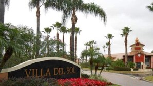 A sign for Villa Del Sol with a landscaped garden and palm trees. - Very Nice apartment , near to Disney (Kissimmee)