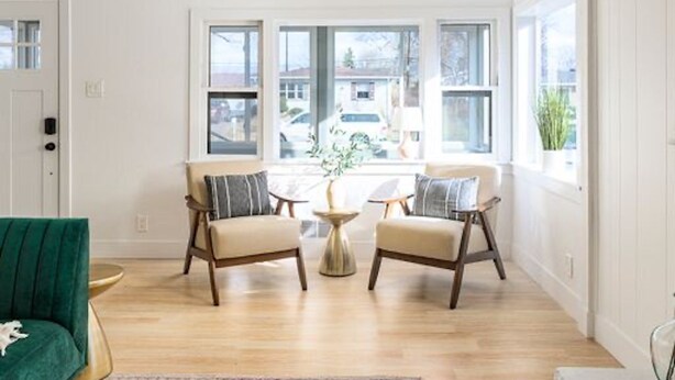 A spacious living room with a green sofa, two armchairs, a coffee table, and large windows offering a view of the outside. - Bright & Modern Retreat - Sleeps 8 - Convenient Location (Wheat Ridge)