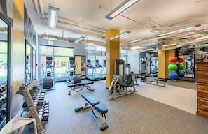 Un gimnasio con cintas de correr, mancuernas y pelotas de ejercicio.