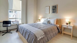 A bedroom with a bed, bedside tables, a desk, and a chair. - Stylish Comfort Meets Spacious Design (Arlington)