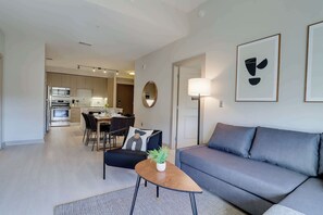 Una sala de estar moderna con un sofá gris, una mesa de centro de madera y un comedor con una mesa y sillas.