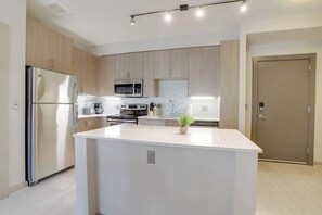 Una cocina moderna con electrodomésticos de acero inoxidable, armarios de madera y una isla central.