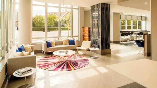 A spacious lobby with a sofa, chairs, a coffee table, and a patterned rug. - Stylish Comfort Meets Spacious Design (Arlington)