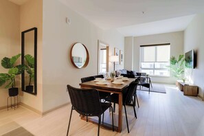 Un comedor con una mesa de madera, sillas negras y un espejo en la pared.
