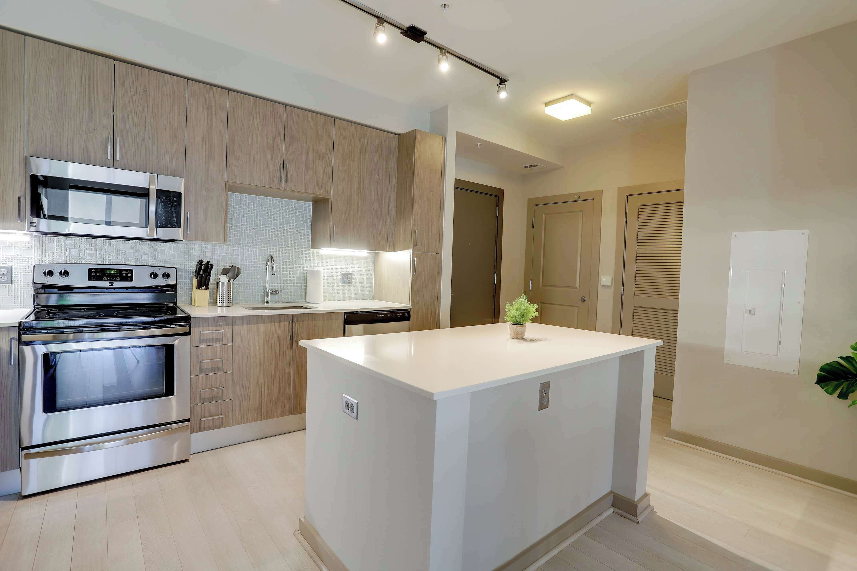 A modern kitchen with stainless steel appliances, wooden cabinets, and a central island.