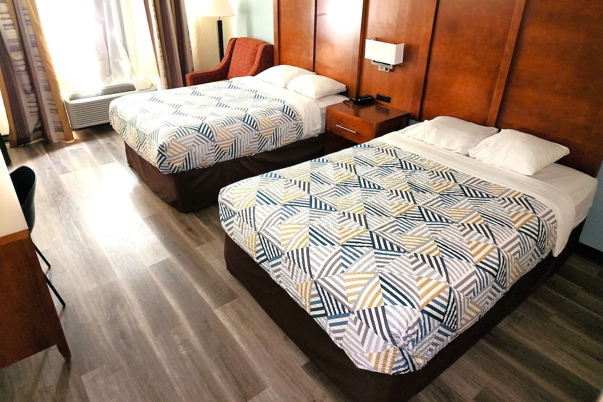 Habitación de hotel con dos camas, un escritorio y una silla.