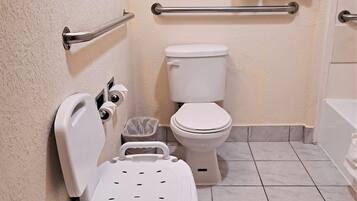 Un baño con inodoro, barras de apoyo, un cesto de basura y una silla de ducha.