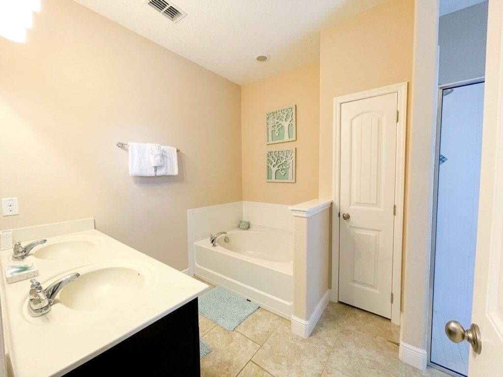 A bathroom with two sinks, a bathtub, and a door.