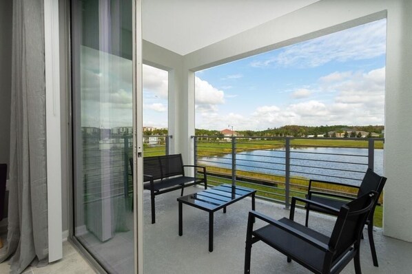 A balcony with a view of a water body and distant buildings. - Sweet Suite Sleeps 6 @ Storey Lake By Shine Villas 2 Bedroom Apts (Kissimmee)