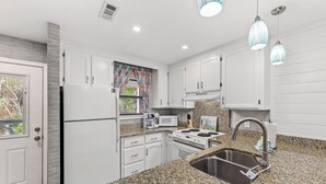 A modern kitchen with white cabinets, granite countertops, a stainless steel sink, a microwave, and a stove. - Short Walk to The Beach! Community Pool! Sleeps 8! (Panama City Beach)