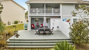 A two-story house with a balcony, a deck with outdoor furniture, and a small garden area. - Short Walk to The Beach! Community Pool! Sleeps 8! (Panama City Beach)