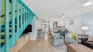 A modern living room with a staircase, a dining area, and a kitchen. - Short Walk to The Beach! Community Pool! Sleeps 8! (Panama City Beach)