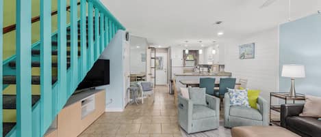 Una sala de estar moderna con una escalera, un comedor y una cocina.
