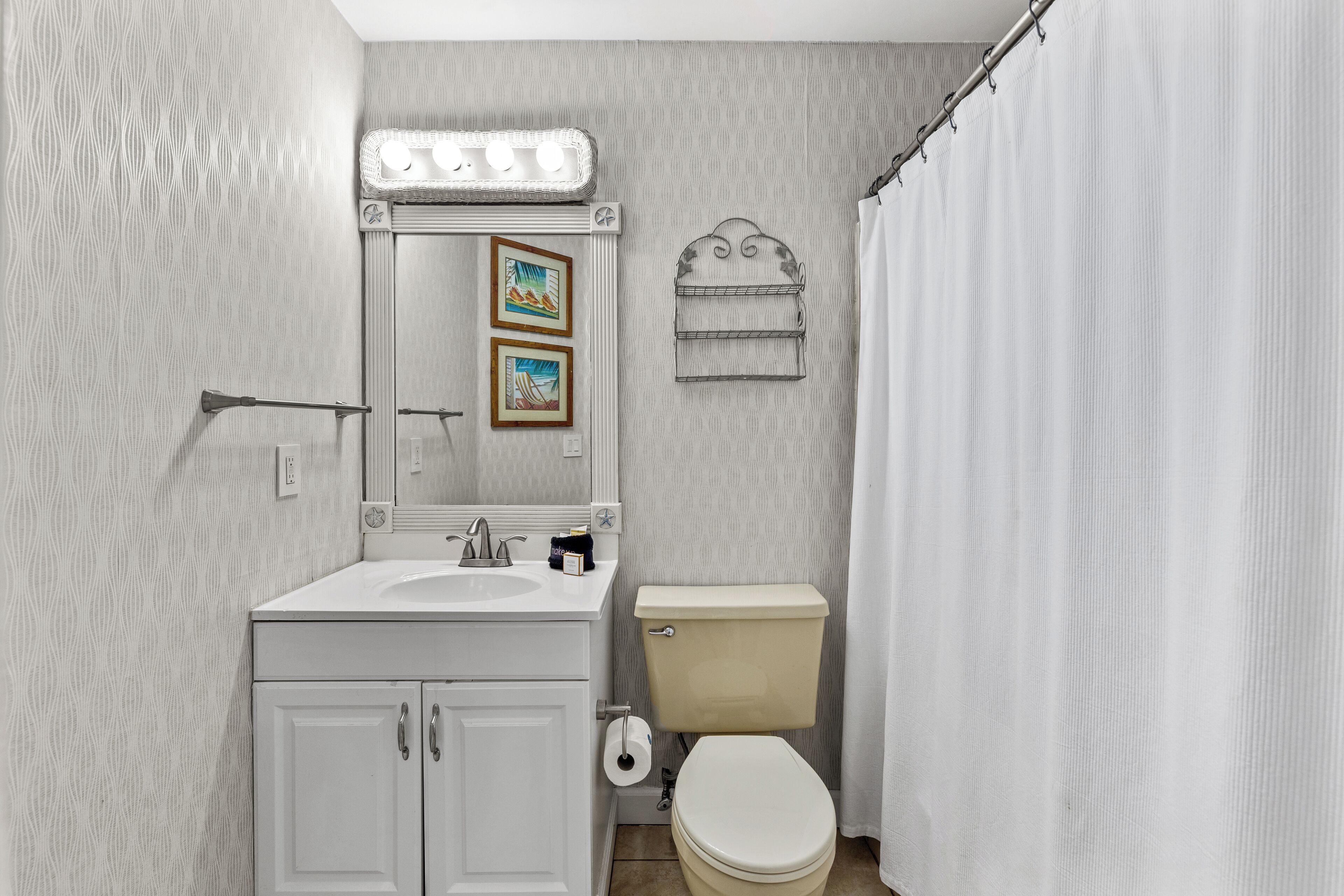 Ein Badezimmer mit Waschbecken, Spiegel, Toilette und Duschvorhang.