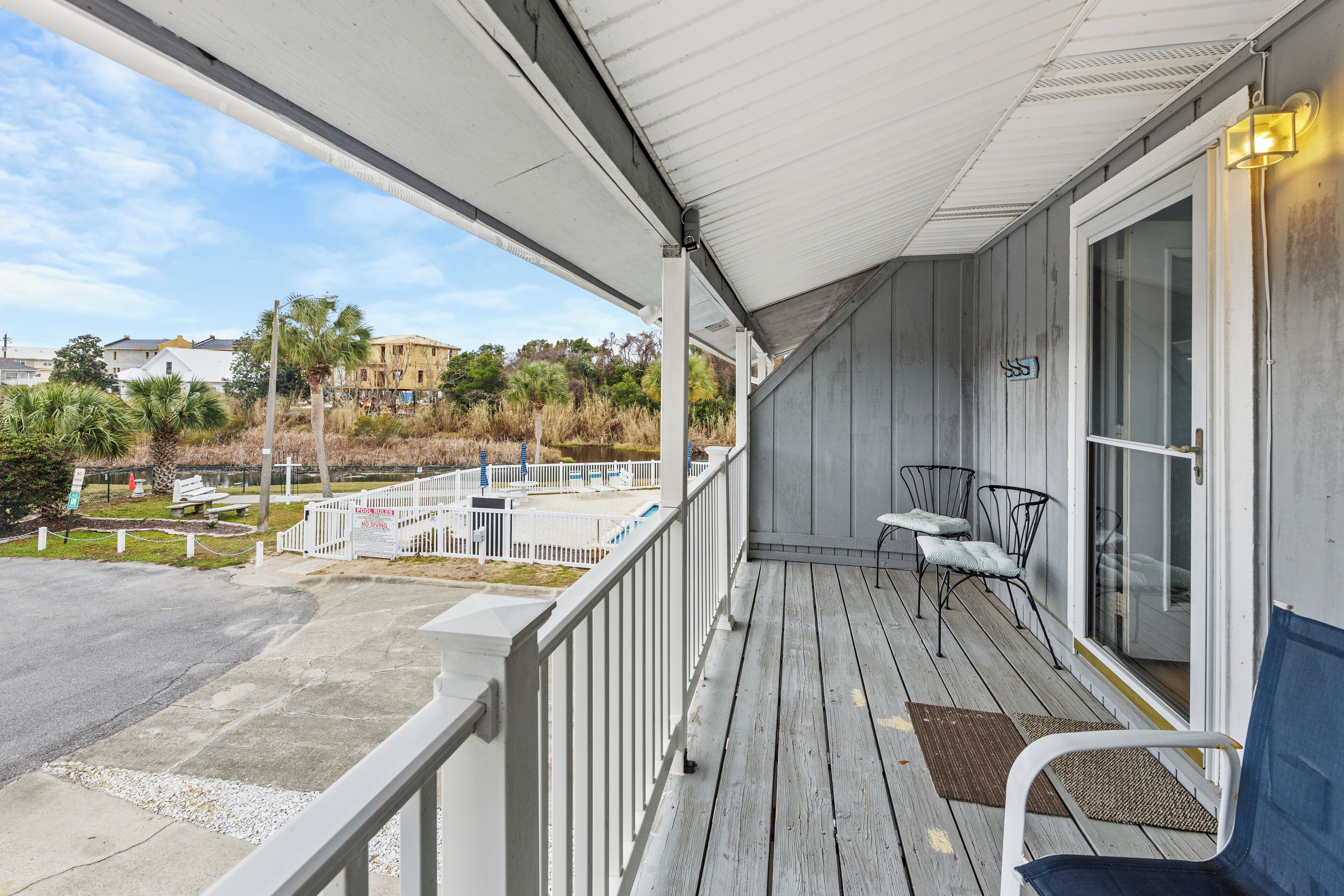 A covered porch with a railing, a bench, and a table.