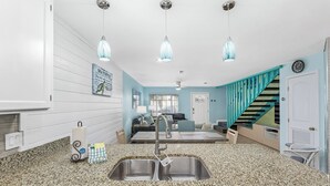 A kitchen with granite countertops, stainless steel sink, and pendant lights. - Short Walk to The Beach! Community Pool! Sleeps 8! (Panama City Beach)